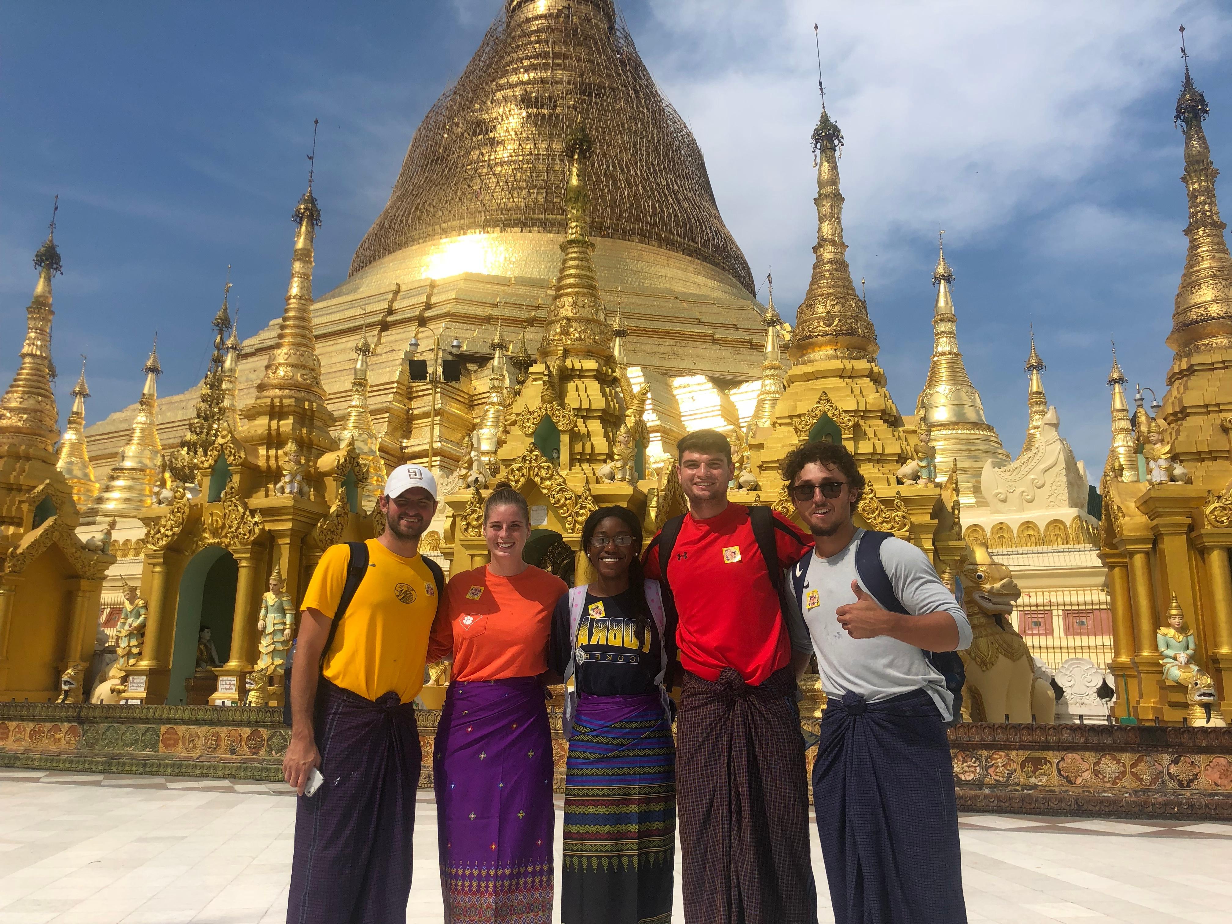 A group of five students pose in front of a temple in Myanmar